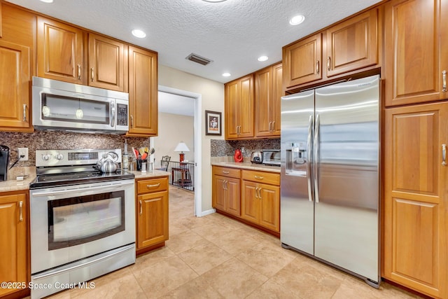 kitchen with decorative backsplash, stainless steel appliances, and a textured ceiling