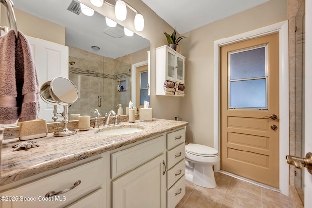 bathroom featuring tile patterned flooring, vanity, toilet, and walk in shower