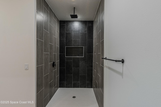 bathroom with a textured ceiling and tiled shower