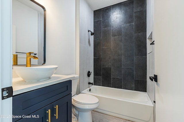 full bathroom with tiled shower / bath combo, vanity, hardwood / wood-style flooring, and toilet