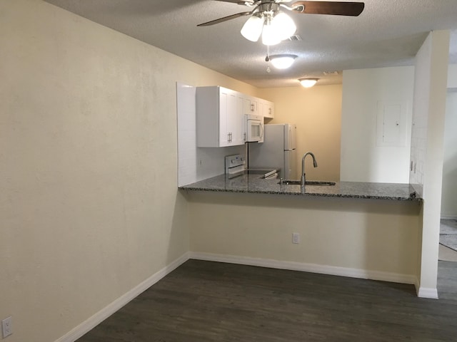 kitchen with sink, dark stone countertops, white cabinets, kitchen peninsula, and white appliances