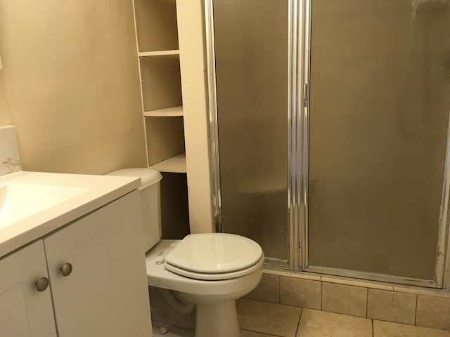 bathroom with a shower with door, vanity, tile patterned flooring, and toilet