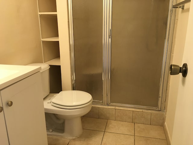 bathroom featuring tile patterned floors, vanity, toilet, and a shower with shower door