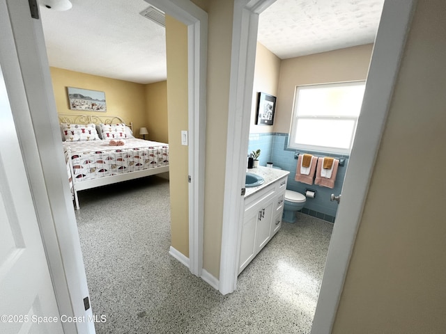 bedroom with tile walls, sink, and a textured ceiling