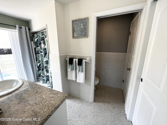 bathroom with vanity, toilet, and tile walls