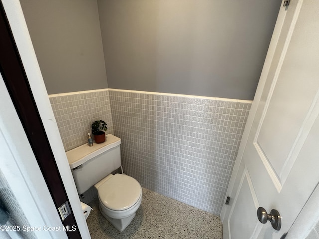 bathroom with tile walls and toilet