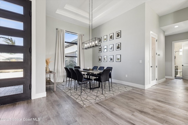 dining space featuring a notable chandelier, a tray ceiling, and light hardwood / wood-style floors