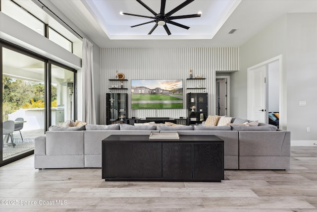 living room featuring a tray ceiling, light hardwood / wood-style floors, and a towering ceiling