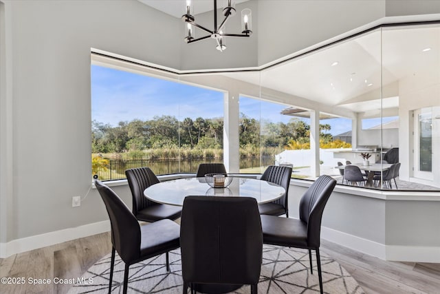 dining space with high vaulted ceiling, a chandelier, and light hardwood / wood-style floors