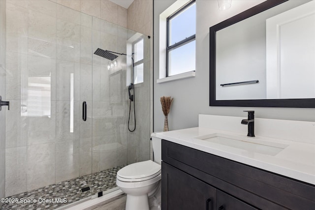 bathroom with walk in shower, vanity, and toilet