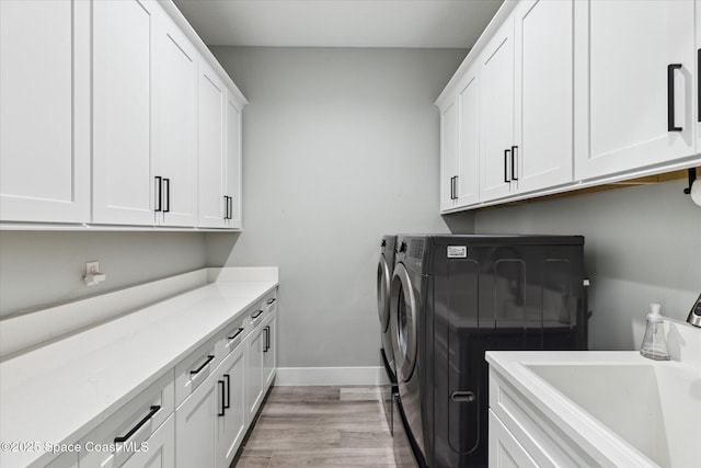 laundry room with cabinets, separate washer and dryer, sink, and light wood-type flooring