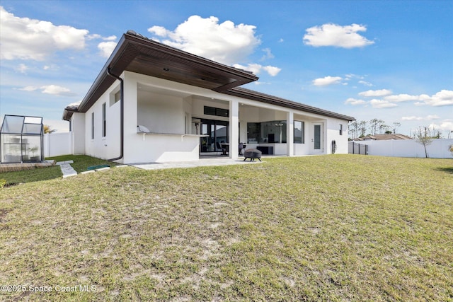 rear view of property with a patio and a lawn