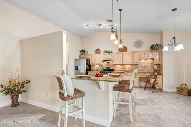 kitchen featuring a breakfast bar, tasteful backsplash, lofted ceiling, stainless steel appliances, and light stone countertops