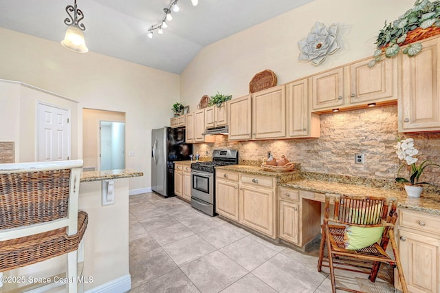 kitchen featuring vaulted ceiling, built in desk, hanging light fixtures, light stone counters, and stainless steel appliances