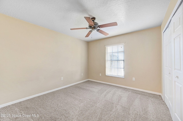 unfurnished bedroom with ceiling fan, carpet floors, a closet, and a textured ceiling