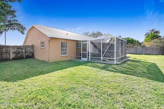 rear view of house with a lanai and a lawn