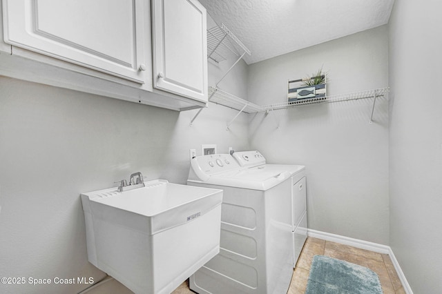 laundry room featuring sink, washer and clothes dryer, cabinets, and light tile patterned flooring