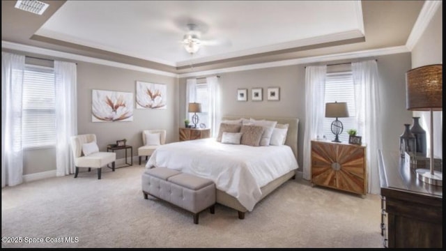 bedroom featuring crown molding, a tray ceiling, and light colored carpet