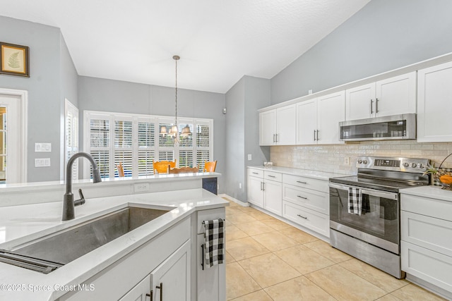 kitchen with sink, appliances with stainless steel finishes, hanging light fixtures, white cabinets, and decorative backsplash