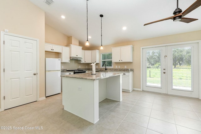 kitchen with sink, white cabinets, white fridge, light stone counters, and a center island with sink