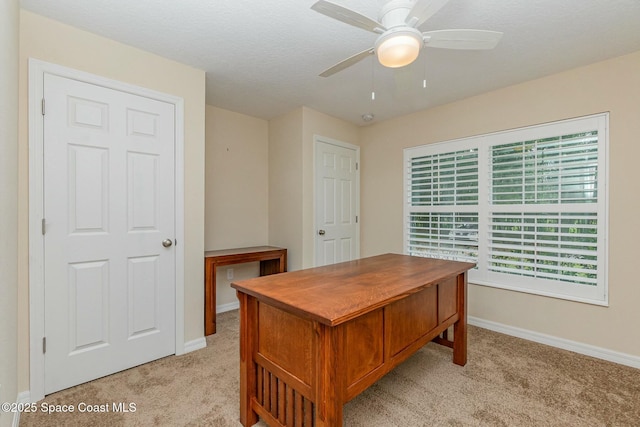 carpeted home office with a textured ceiling and ceiling fan