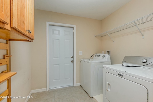 laundry room featuring light tile patterned floors, washing machine and dryer, and cabinets