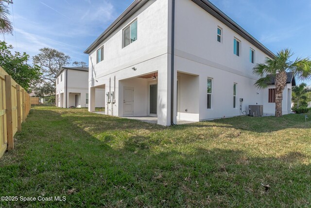 rear view of property featuring a patio, a lawn, and central air condition unit