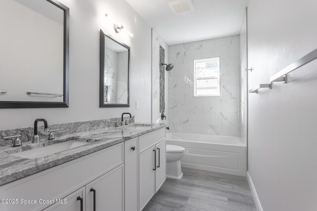 full bathroom with vanity, hardwood / wood-style flooring, toilet, and tiled shower / bath