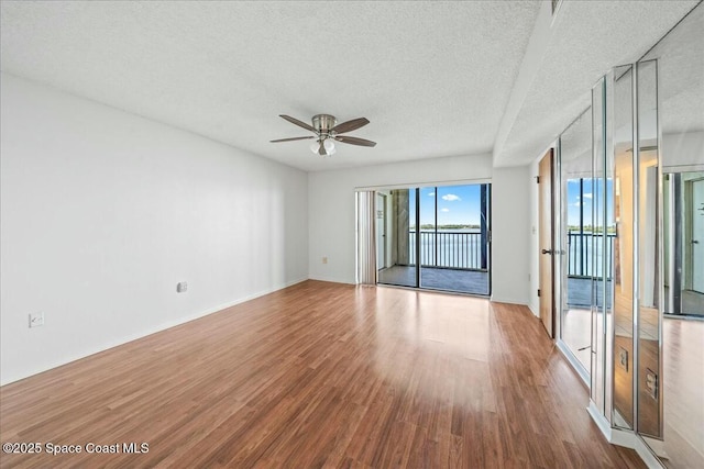 unfurnished room featuring a textured ceiling, ceiling fan, and light hardwood / wood-style flooring