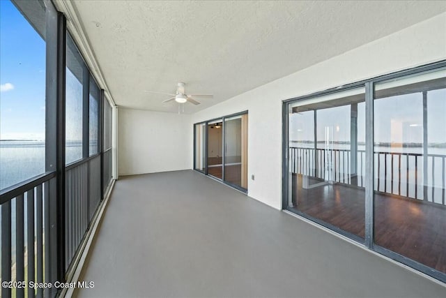 unfurnished sunroom with a water view and ceiling fan