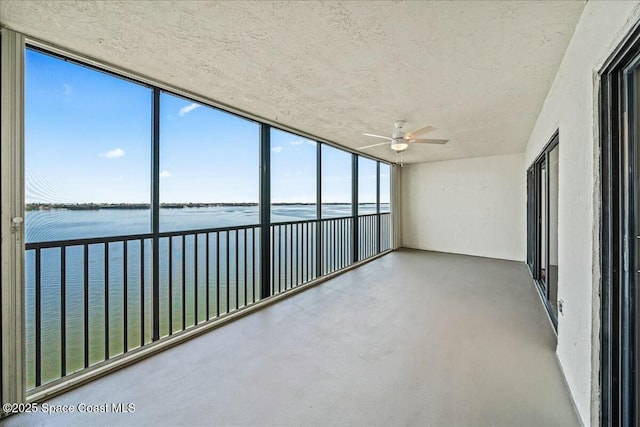 unfurnished sunroom featuring a water view and ceiling fan