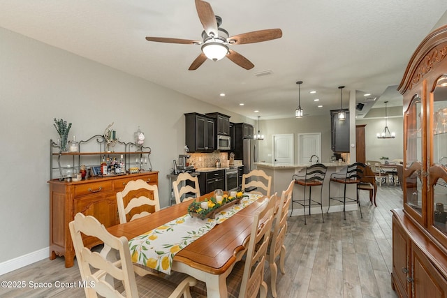 dining area featuring ceiling fan with notable chandelier and light hardwood / wood-style floors