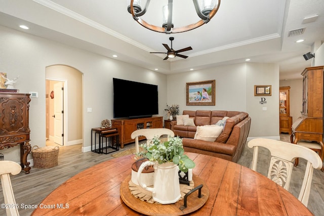 living room featuring ornamental molding, ceiling fan, light hardwood / wood-style floors, and a tray ceiling