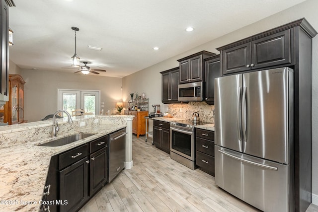 kitchen featuring stainless steel appliances, tasteful backsplash, sink, and light stone counters