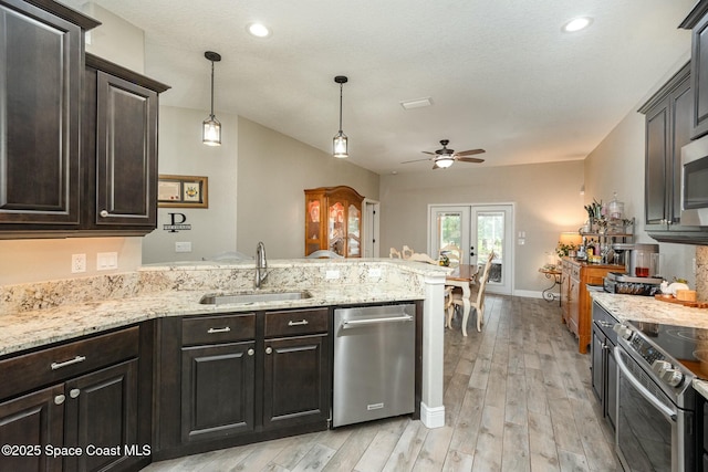 kitchen with sink, stainless steel appliances, decorative light fixtures, kitchen peninsula, and light wood-type flooring