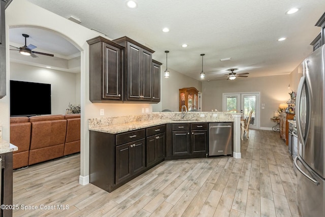 kitchen featuring sink, stainless steel appliances, dark brown cabinetry, decorative light fixtures, and kitchen peninsula