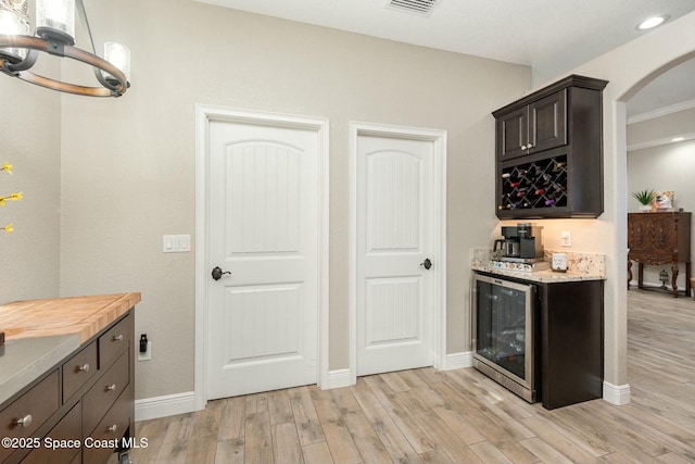 kitchen with wooden counters, light wood-type flooring, beverage cooler, and dark brown cabinetry