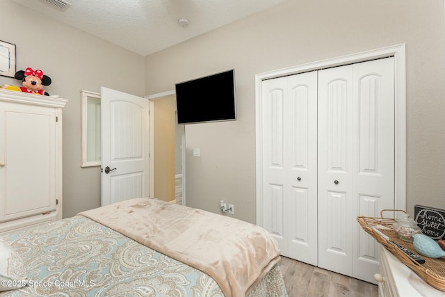 bedroom featuring a closet, light hardwood / wood-style flooring, and a textured ceiling