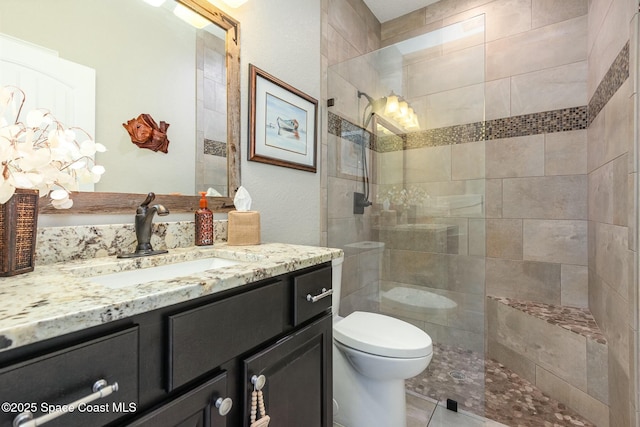 bathroom featuring vanity, a tile shower, and toilet