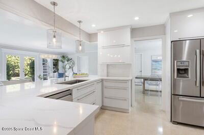 kitchen with sink, appliances with stainless steel finishes, white cabinets, decorative light fixtures, and kitchen peninsula