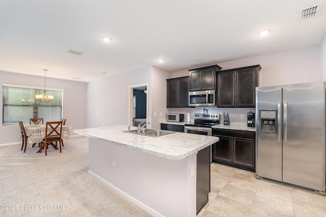 kitchen featuring pendant lighting, sink, a kitchen island with sink, stainless steel appliances, and light carpet