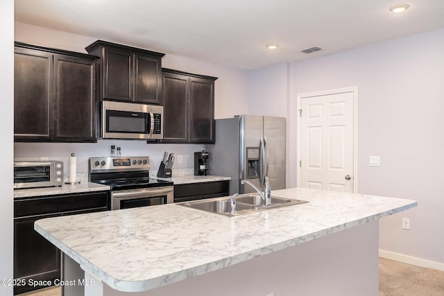 kitchen featuring appliances with stainless steel finishes, sink, a center island with sink, and dark brown cabinetry