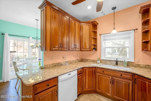 kitchen with light stone counters, dishwasher, sink, and hanging light fixtures