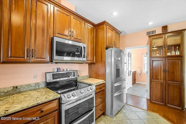 kitchen featuring stainless steel appliances, light stone countertops, and light tile patterned floors