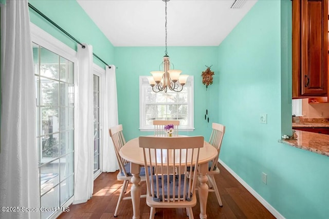 dining area with plenty of natural light, dark wood-type flooring, and an inviting chandelier