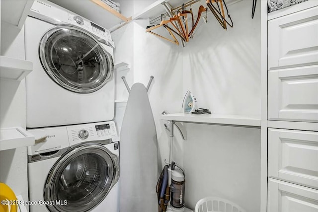 laundry area with stacked washer / dryer and cabinets