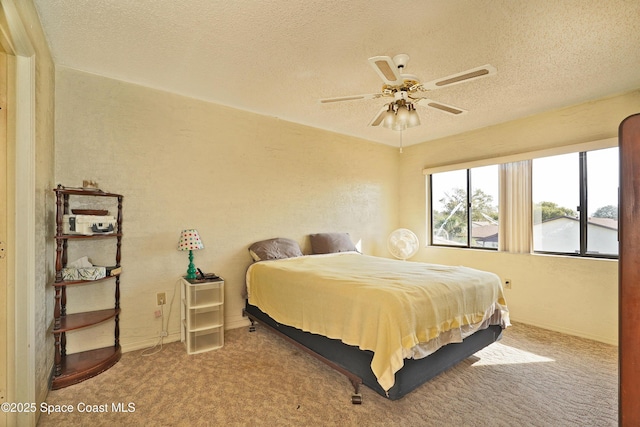 bedroom with ceiling fan, light colored carpet, and a textured ceiling