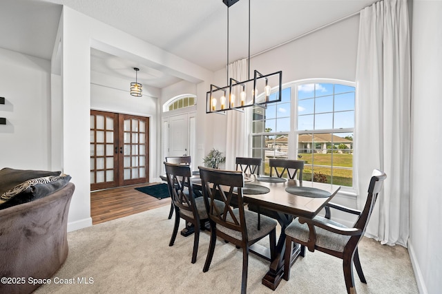 carpeted dining room with a notable chandelier and french doors