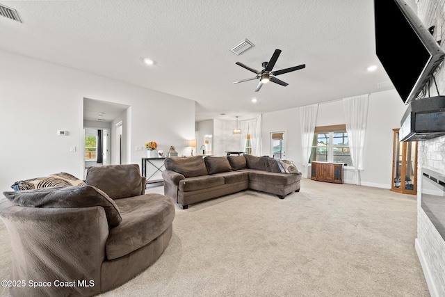 carpeted living room featuring ceiling fan and a textured ceiling