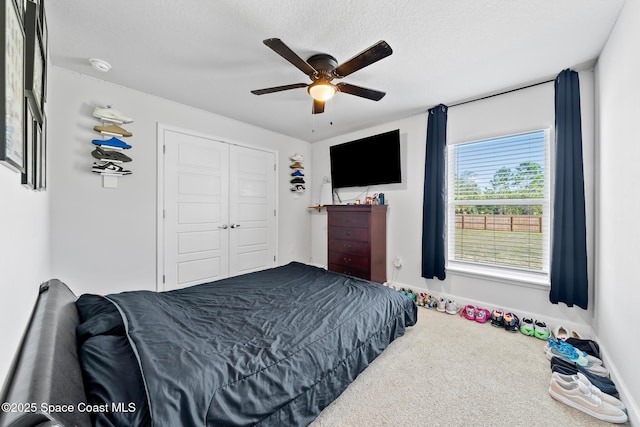 carpeted bedroom featuring ceiling fan, a closet, and a textured ceiling